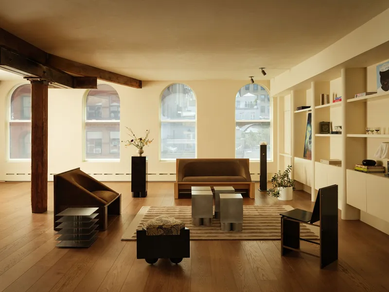 Open loft space with arched windows, exposed timber beams and warm afternoon light