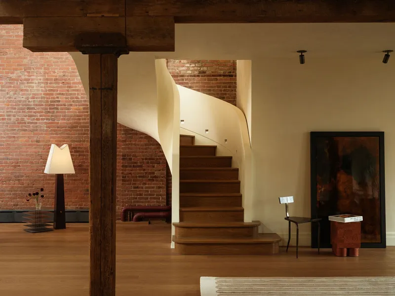 Sculptural timber staircase with flowing white balustrade against exposed brick wall