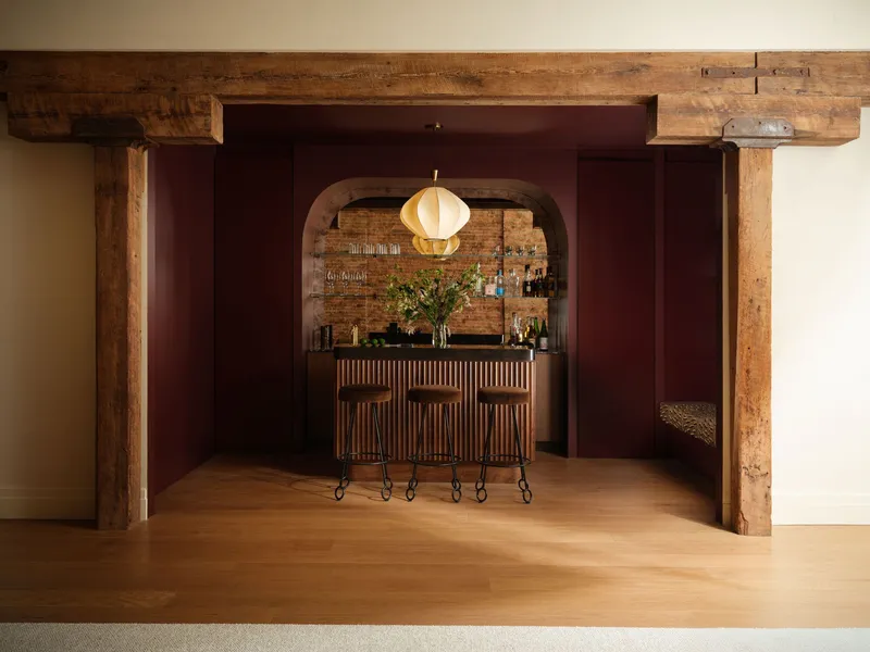 Bar alcove framed by timber posts and recessed maroon paneling with pendant light