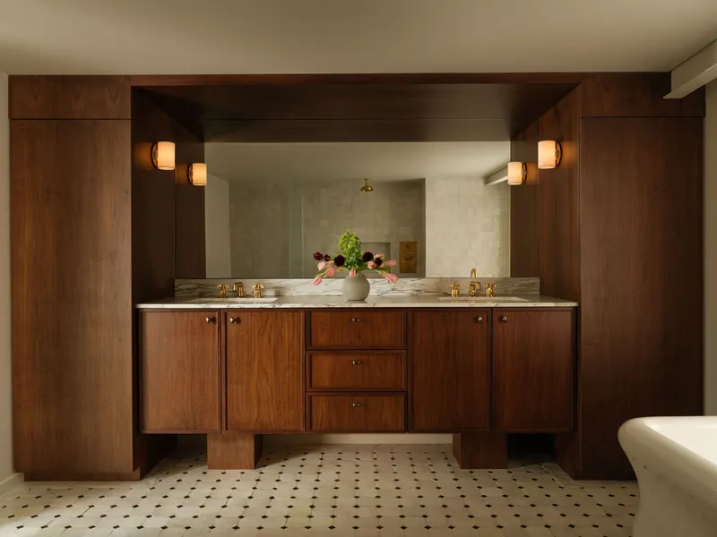 Walnut double vanity with stone countertop, framed mirror, and black and white mosaic floor tile