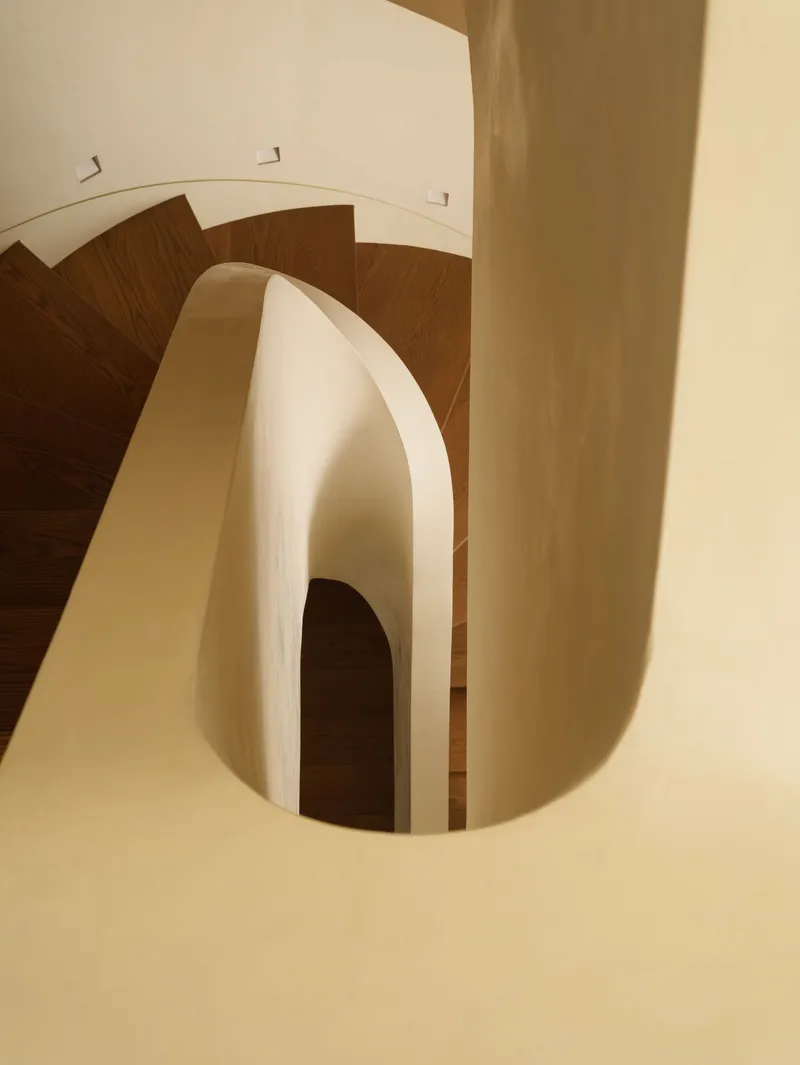 Top-down view of curved stairwell with timber treads and arched opening below