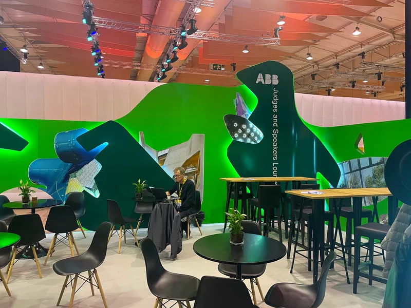 A visitor seated at a high table near green walls adorned with large photographic collages