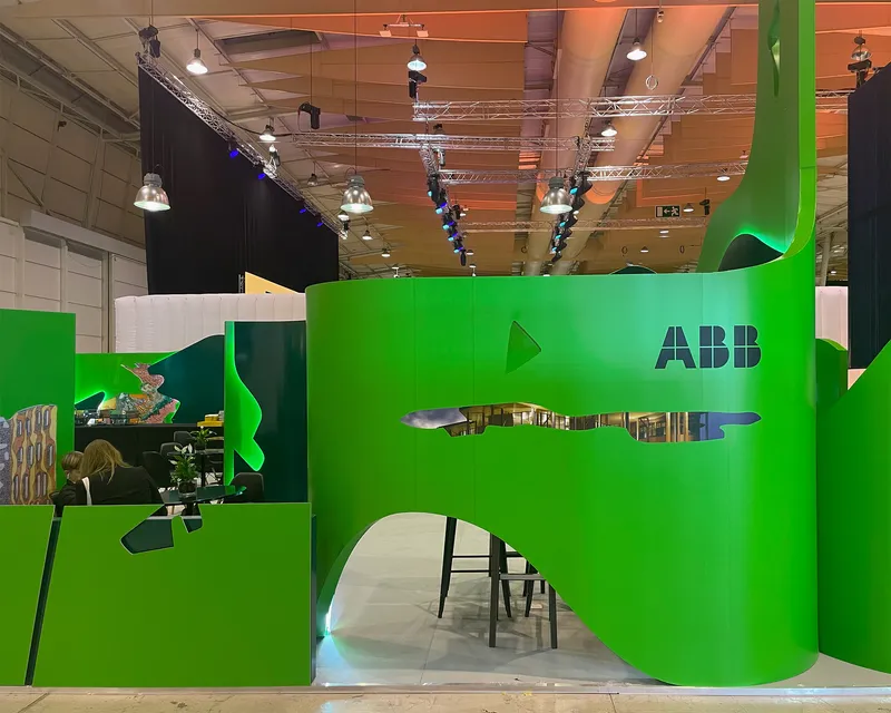 Curved green wall with horizontal slot opening and table visible through the aperture