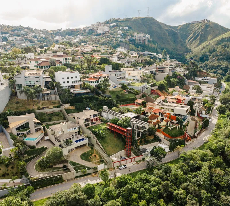 Aerial view of the residence with red steel tower on a sloping hillside neighborhood