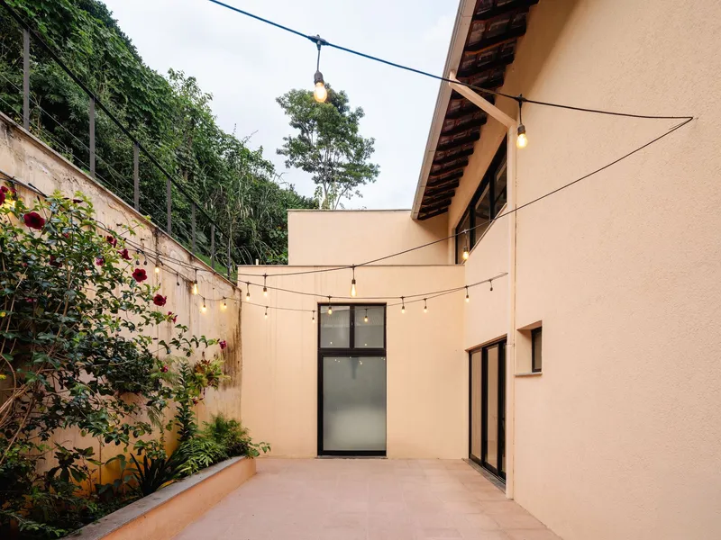 Enclosed courtyard with stuccoed walls, string lights overhead, and planted bed against a retaining wall
