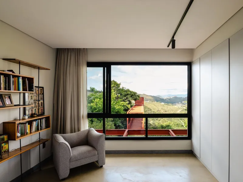 Reading nook with bookshelves and picture window framing the red steel structure and valley beyond