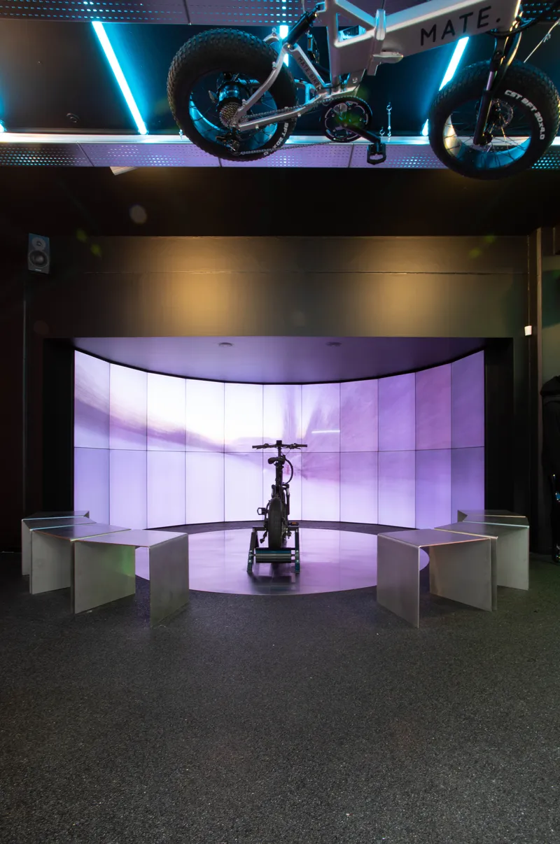 Curved display alcove with backlit purple panels and a bicycle on a central platform