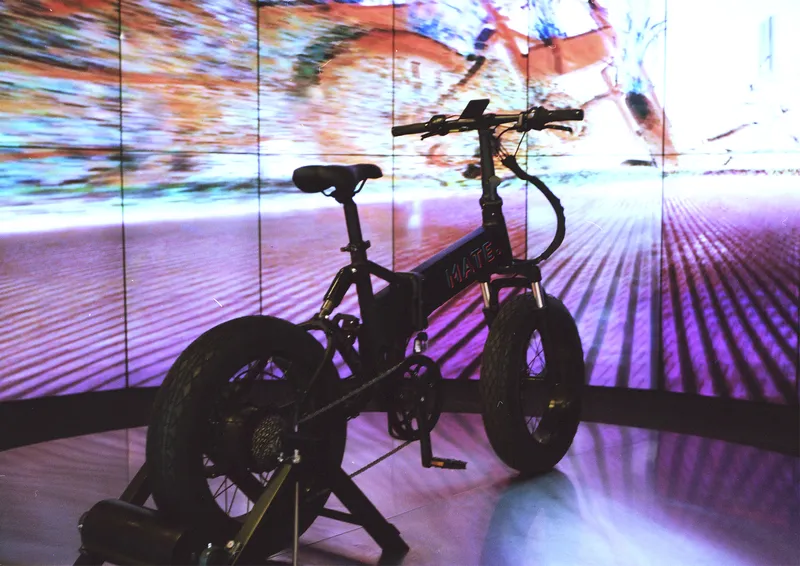 Silhouetted bike on a stand against a multiscreen video wall projection