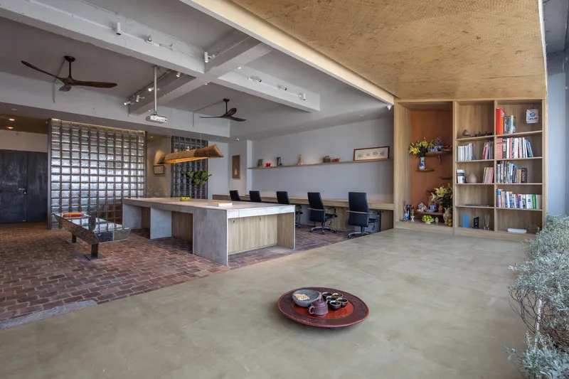 Open office space with exposed beams, brick flooring, and a glass block partition wall