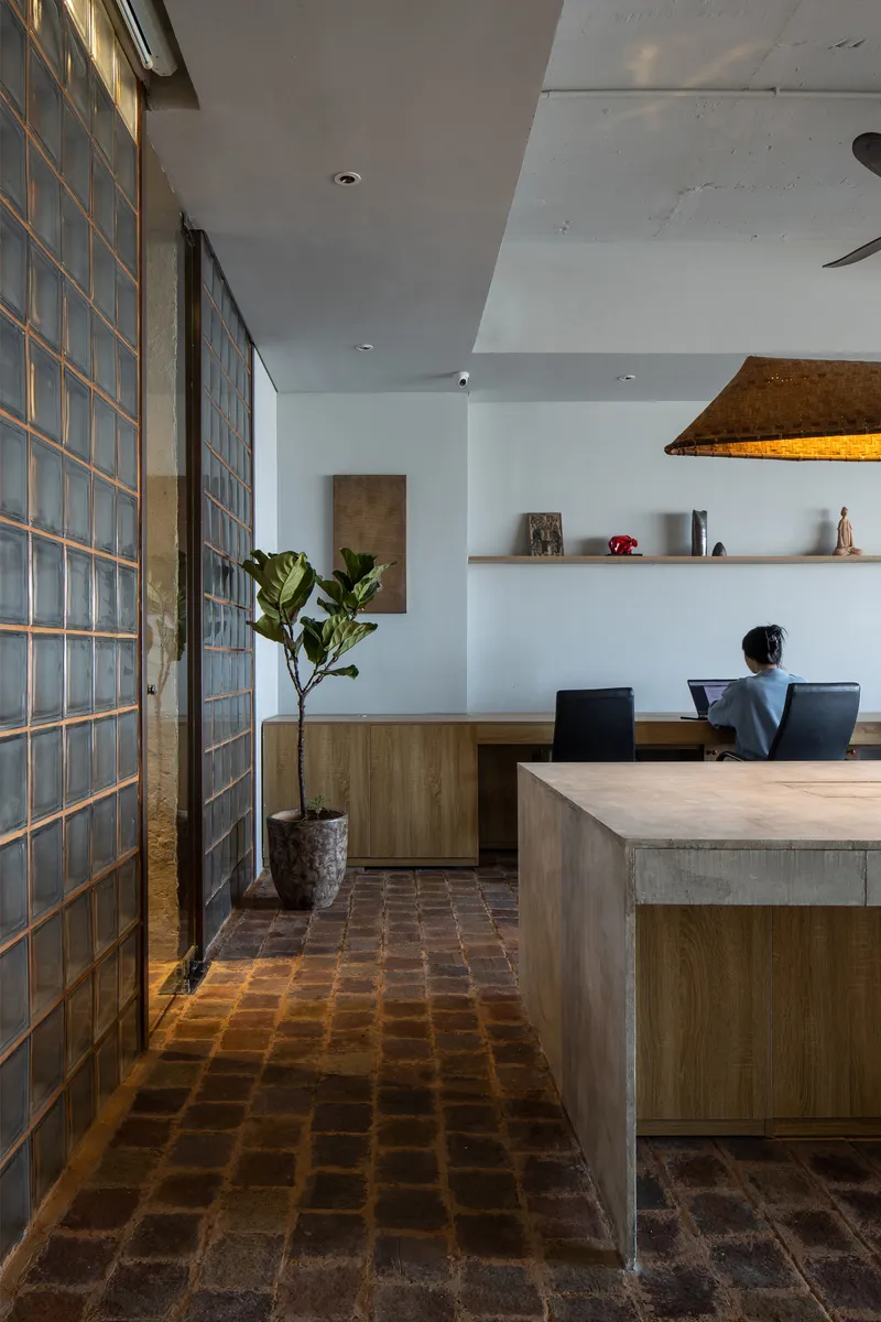Glass block partition wall flanked by reclaimed brick floor leading to timber and concrete dining table