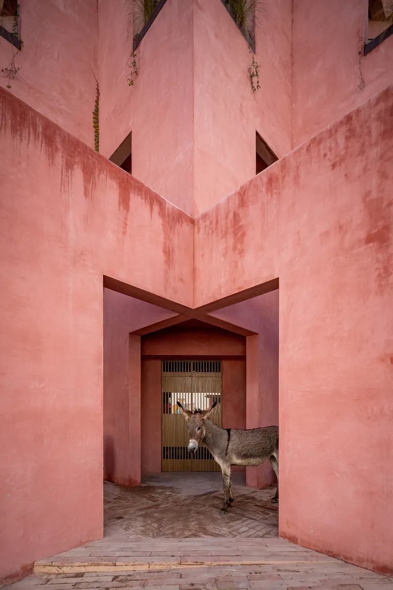 Pointed facade corner framing an arched portal with a deer sculpture standing in the threshold