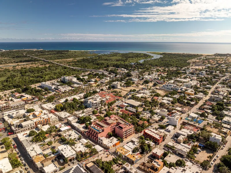 Aerial view of the red plaster building within a coastal town extending toward the ocean under scattered clouds