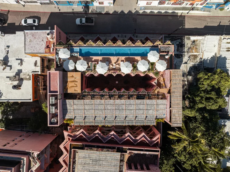 Drone view showing the sawtooth roof, white umbrellas on the terrace and adjacent street with parked cars