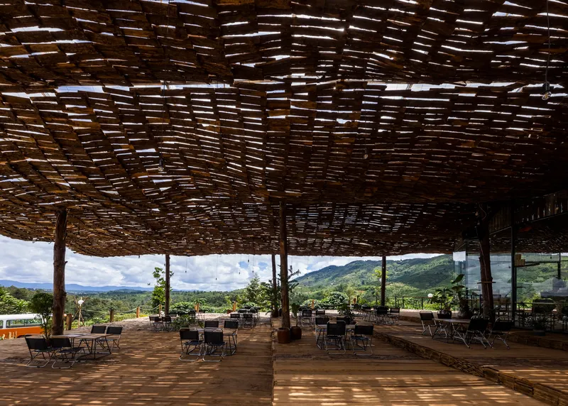 Dappled light filtering through the woven bamboo ceiling onto the timber deck and seating below