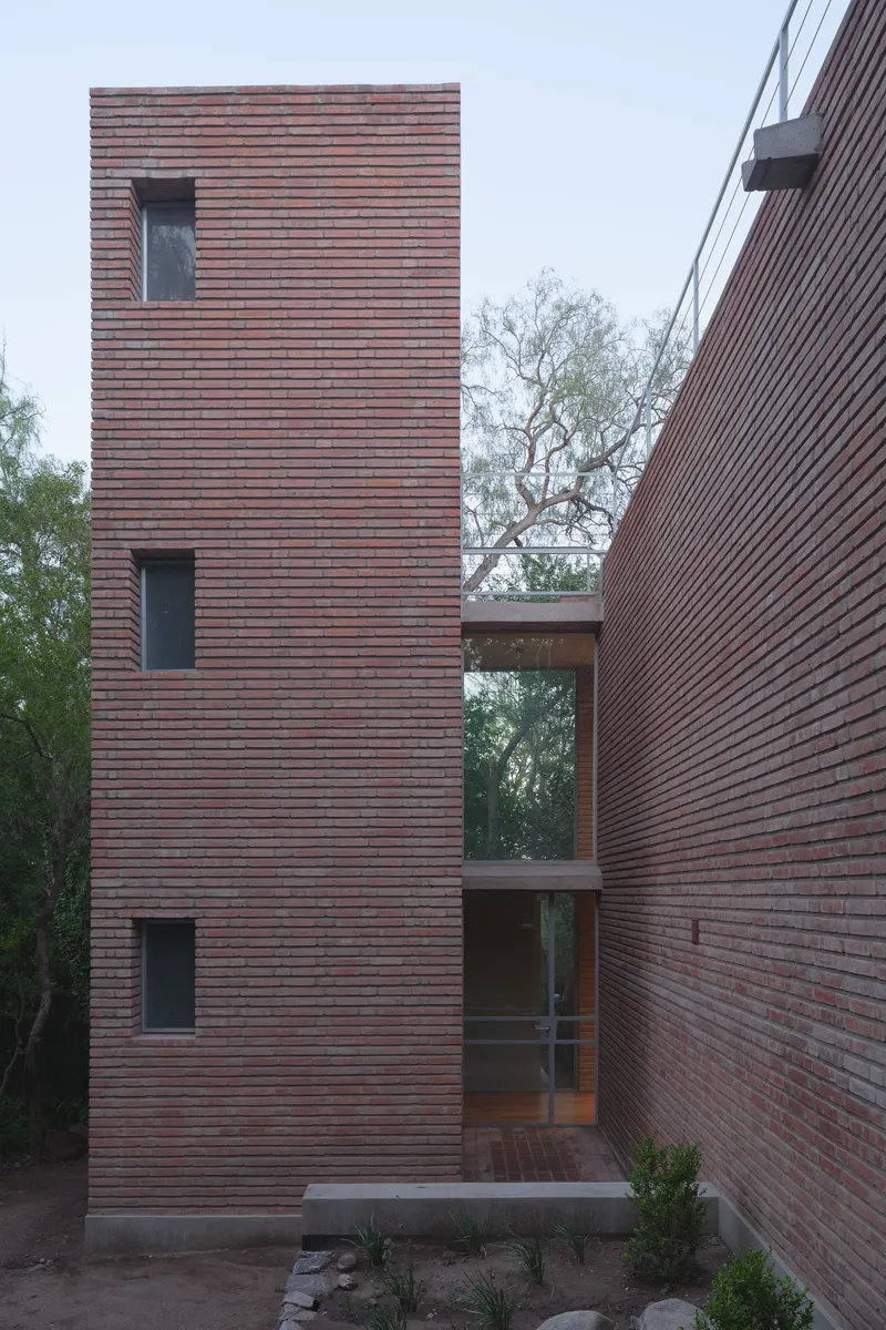 Courtyard view showing three-story brick tower and glazed bridge connecting parallel volumes