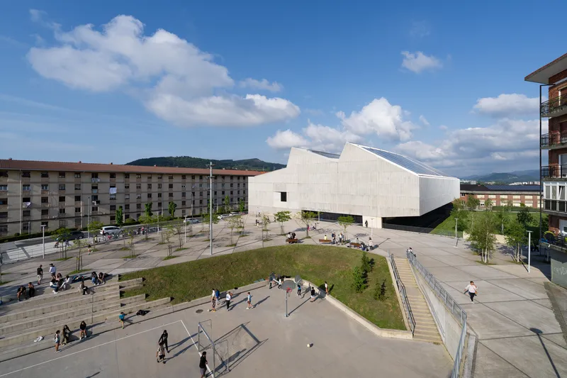 Elevated view of the angular volume and surrounding plaza with stepped seating areas and walking figures