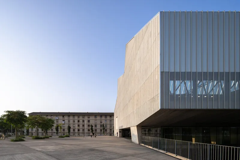 Corner view showing the cantilevered upper volume with perforated metal screen band at sunset