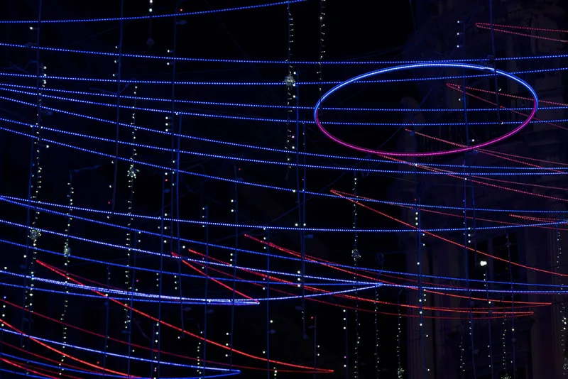 Tilted view of the glowing elliptical ring intersecting layers of horizontal blue and red LED strands