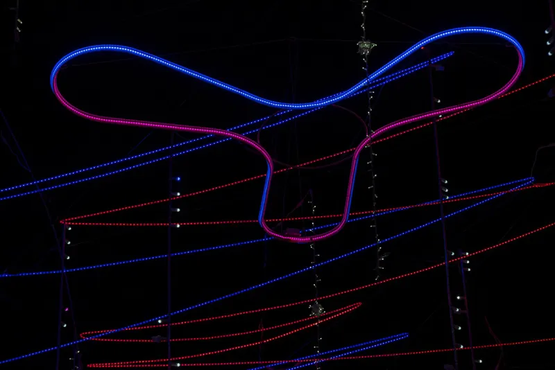 Close-up of curved LED tube forming a looping gesture against parallel red and blue linear light strands