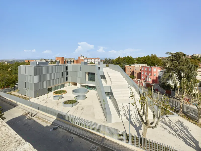 Elevated view of the triangular courtyard with circular planters and the metal-clad volumes surrounded by trees