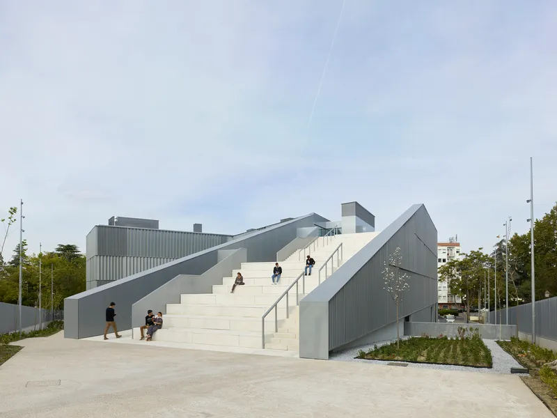 Wide exterior staircase with metal balustrades ascending toward the building with people sitting and walking