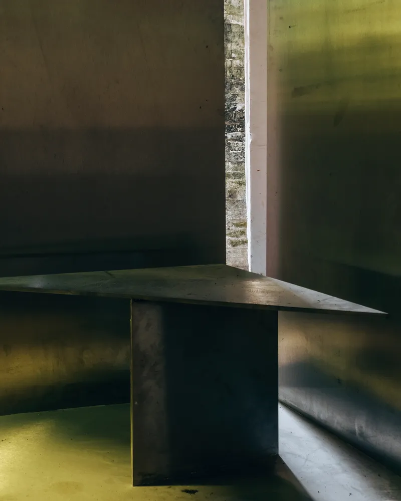 Detail of brass bench ledge meeting a vertical brass wall panel and doorway