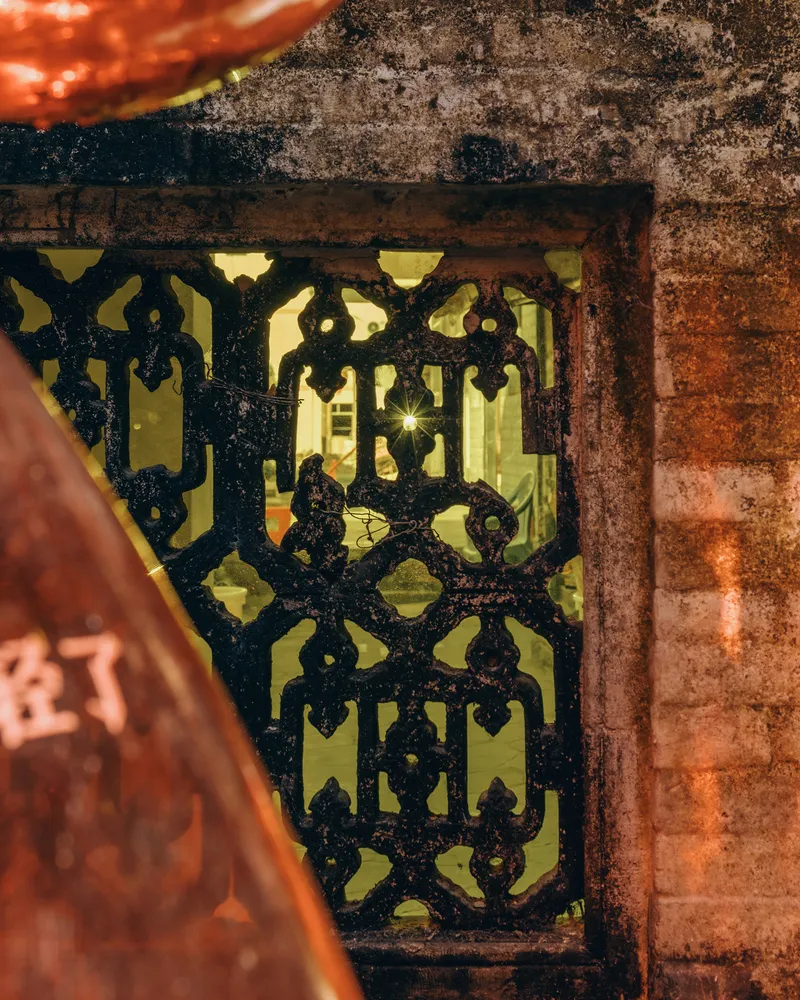 Ornate cast iron grate set within weathered brick opening at dusk