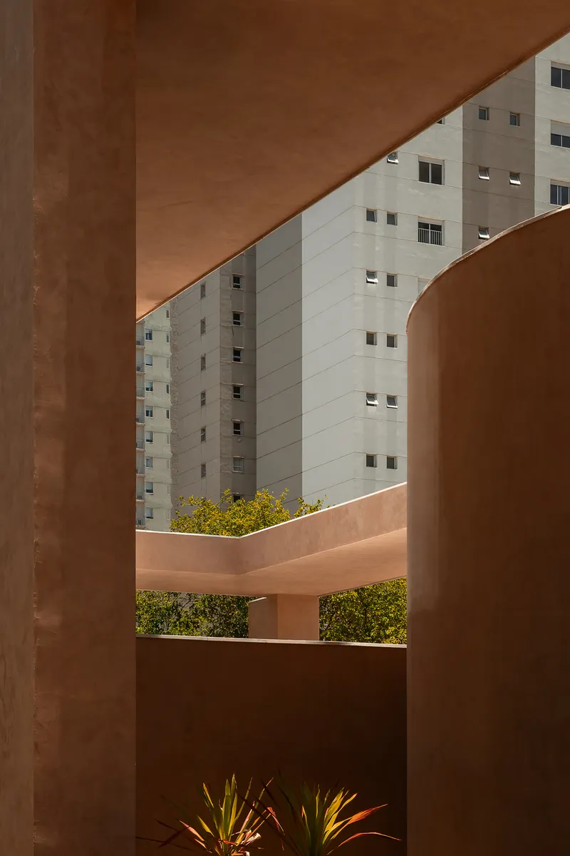 Framed view through terracotta columns showing a residential tower beyond rooftop planted terraces