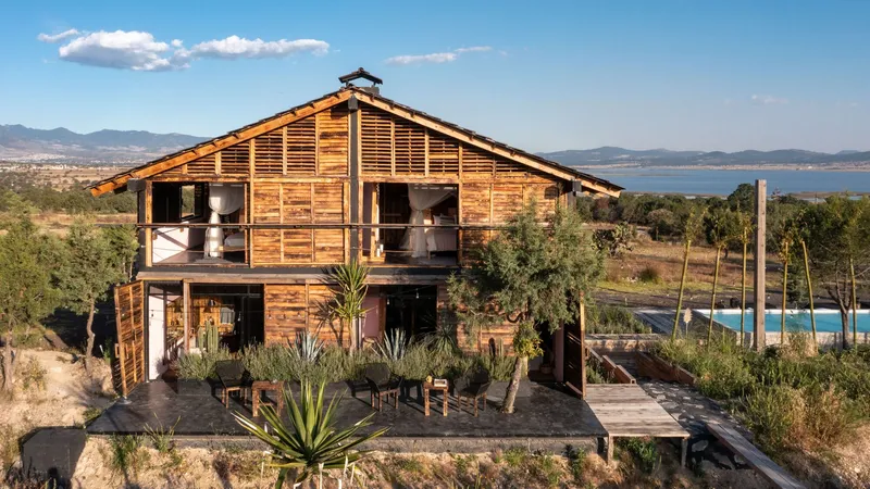 Two-story timber structure with louvered upper level and open ground floor terrace at golden hour