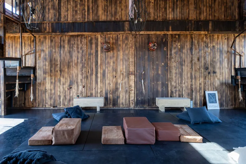 Double-height interior space with vertical timber walls, leather floor cushions and suspended lantern fixtures
