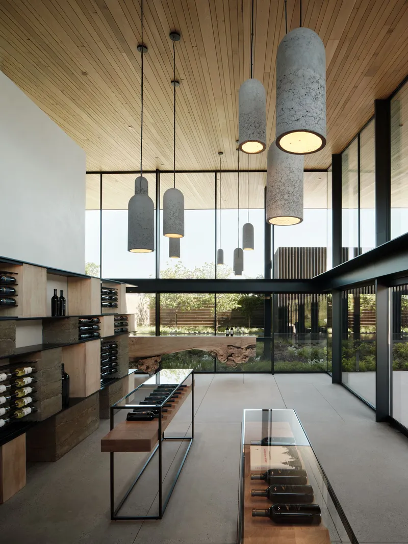 Double-height interior with cylindrical pendant lights suspended from a timber slatted ceiling overlooking a courtyard