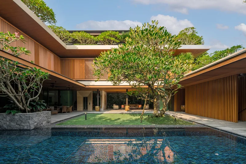 Courtyard view with central pool, vertical timber cladding, and rooftop gardens framing a central tree