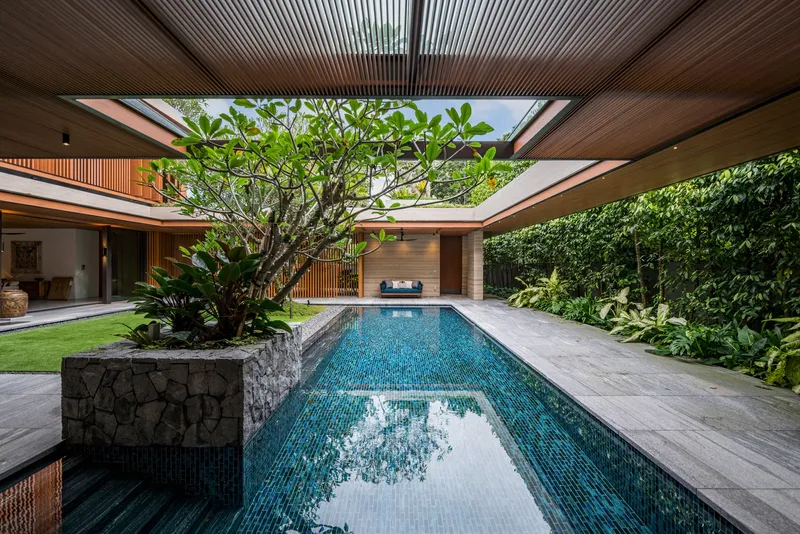 Interior courtyard pool with slatted timber ceiling, planted bed, and a frangipani tree at center