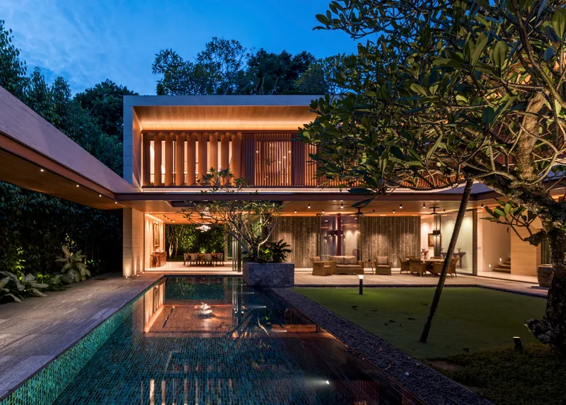 Courtyard pool reflecting the two-story volume with glass walls and uplift timber screens at twilight