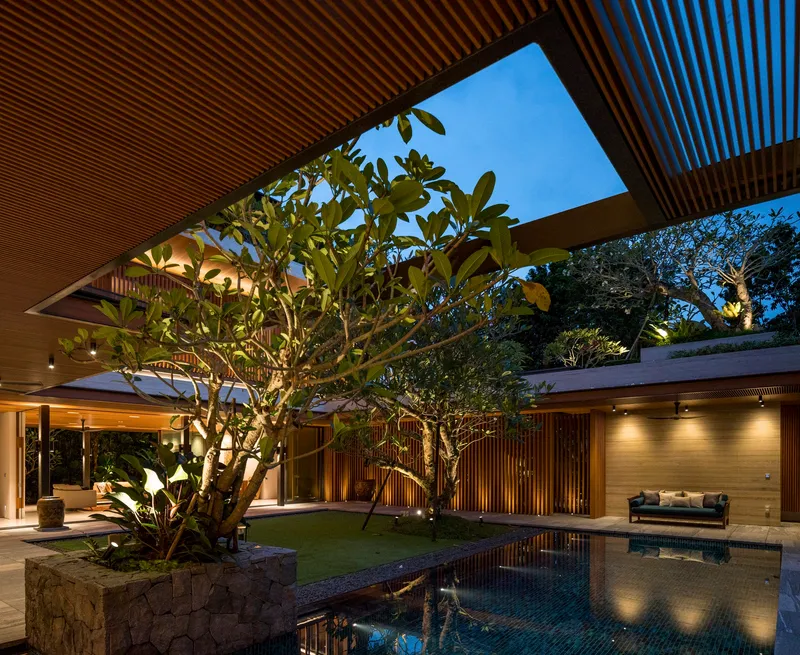 Central courtyard with planted frangipani tree, reflecting pool, and slatted timber ceiling opening to sky