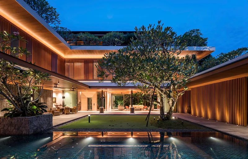 Evening view across the courtyard pool showing two-story timber louvered facades and planted terraces