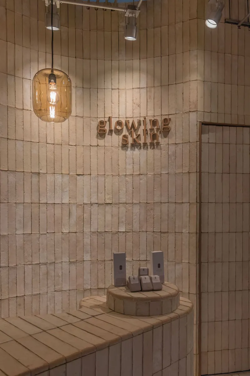 Curved wood-tiled wall with branded signage and amber glass pendant light overhead