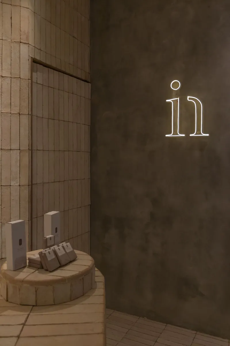 Corner view showing wood-tiled wall meeting concrete with illuminated neon numerals
