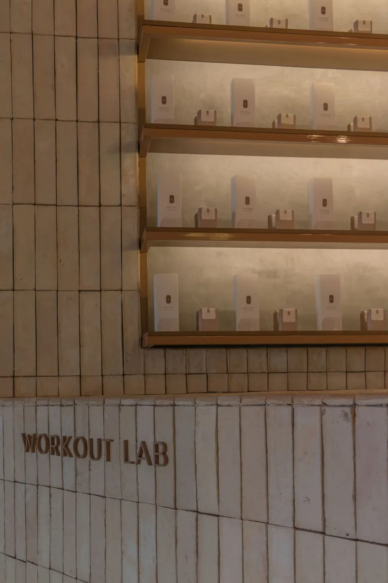 Tiled wall with integrated timber shelves displaying glass bottles under recessed lighting