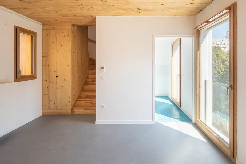 Living space with timber-framed glass doors opening to a balcony under morning sunlight
