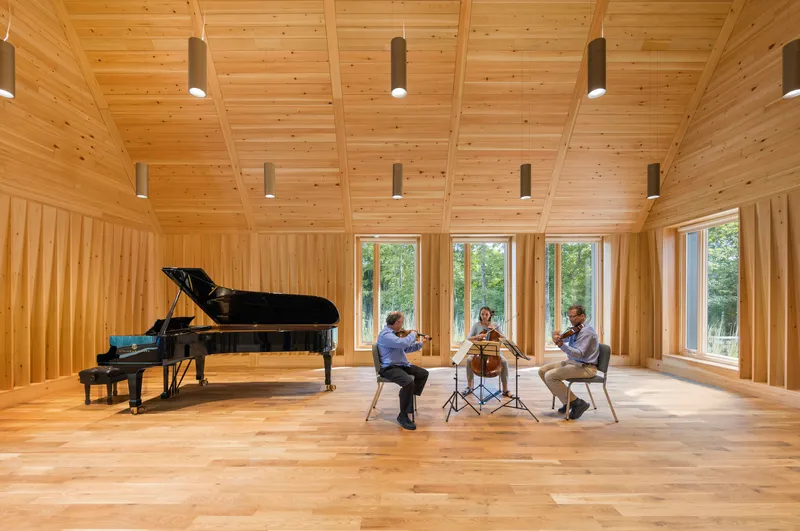 Chamber ensemble rehearsing in the wood-clad space with views to the landscape beyond