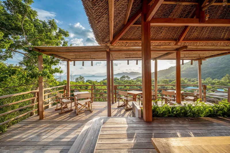 Covered deck with timber columns and cable railing framing mountain vista beyond