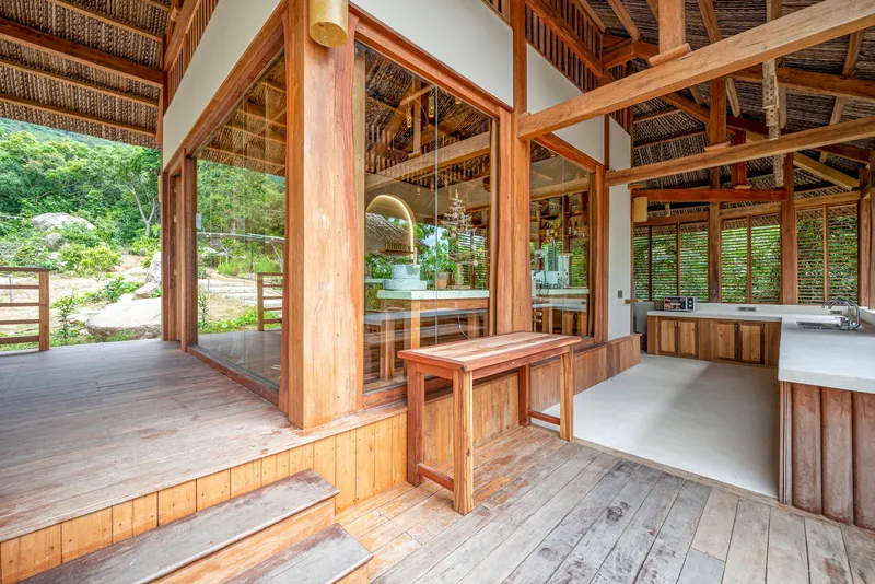 Interior threshold between timber deck and concrete floor with glass partition and louvered screens beyond