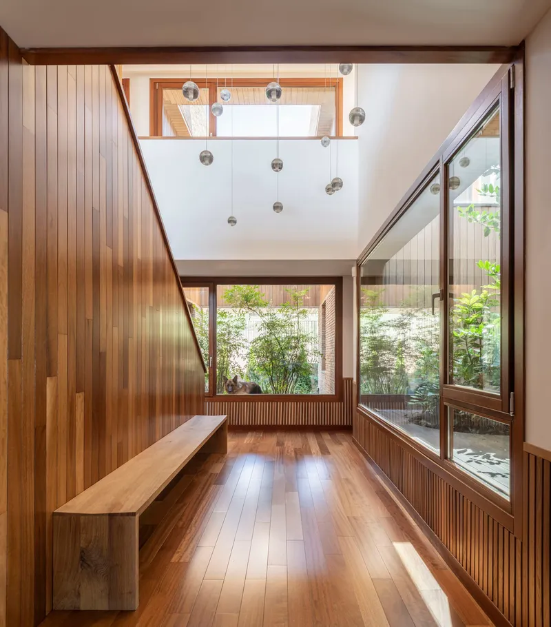 Double-height entryway with vertical timber cladding and glass pendant lights above
