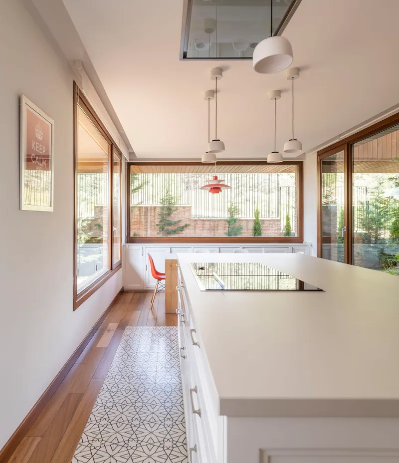 Kitchen with patterned floor tiles and timber-framed windows overlooking a planted courtyard