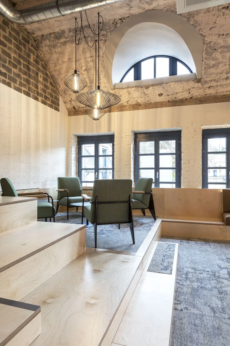 Dining space with exposed brick walls, wire-frame pendant lights, and an arched window above