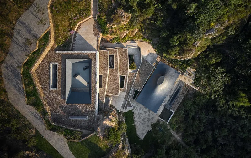 Drone view showing gravel-covered rooftops and courtyards arranged among rocky outcrops and winding pathways