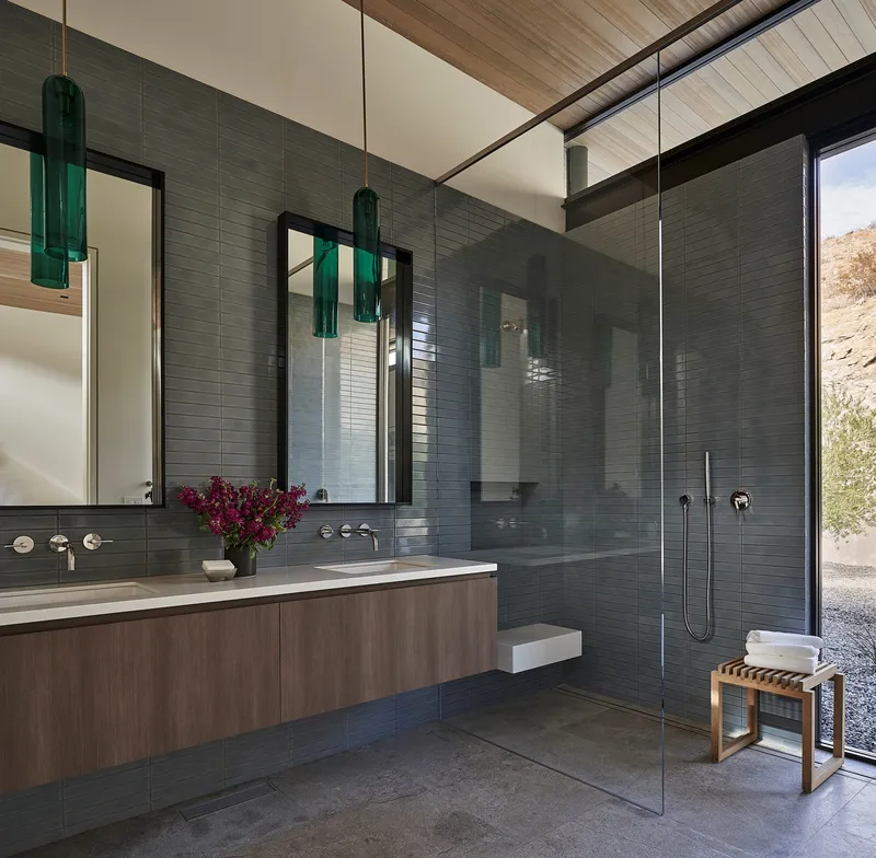 Bathroom with grey tile wall, floating vanity, and glass-enclosed shower stall
