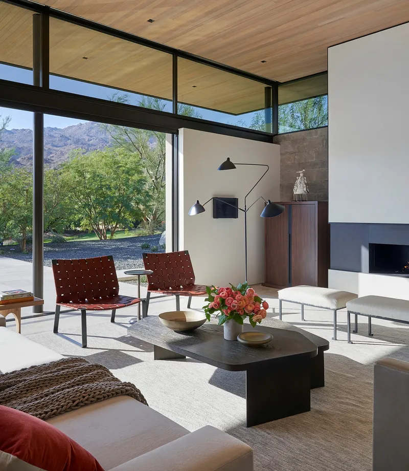 Living room with clerestory windows framing views of desert trees and hills in afternoon light