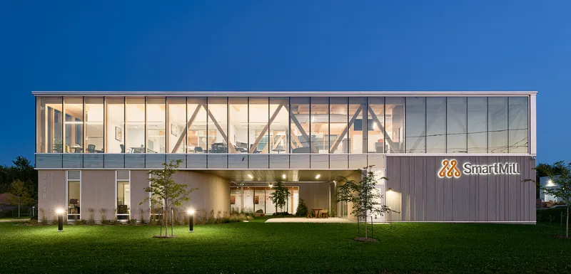 Two-story facade with diagonal timber bracing and corrugated metal cladding under a deep blue evening sky